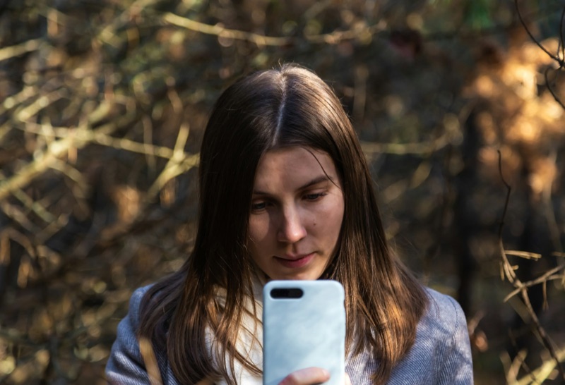 Jonge vrouw kijkt bedachtzaam naar haar telefoon